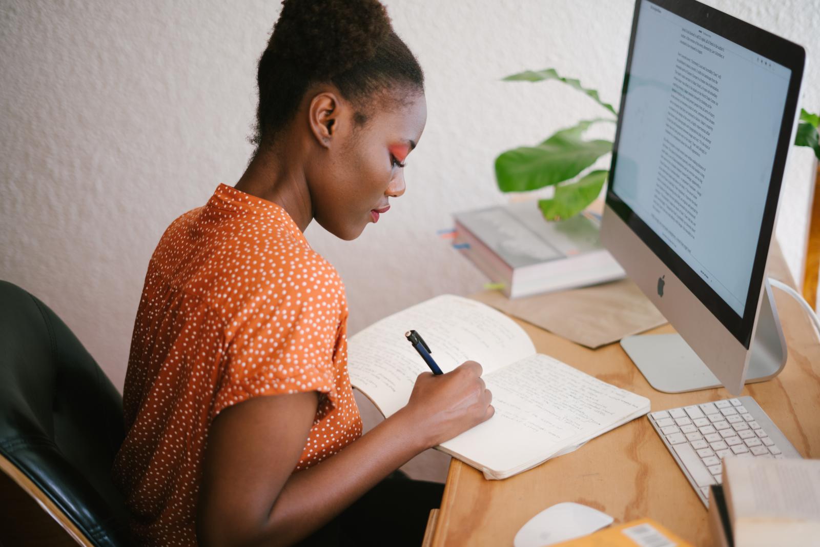 A young black woman writing in a notebook